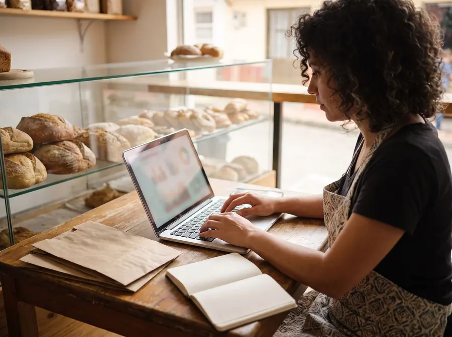 Dueña de una panadería cargando la información de su negocio en el portátil