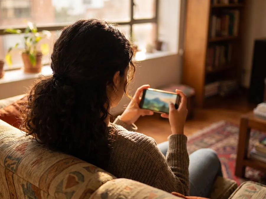 Mujer viendo un video en su celular en la sala de su casa