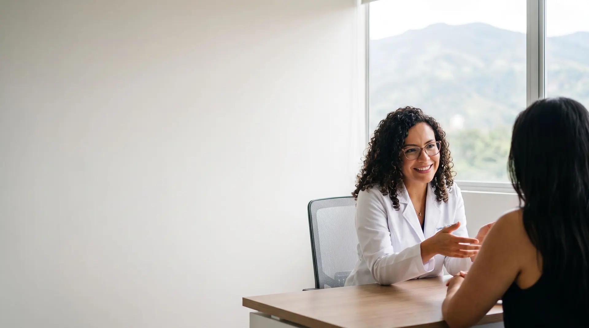 Dermatóloga conversando con una paciente en su consultorio en Medellín